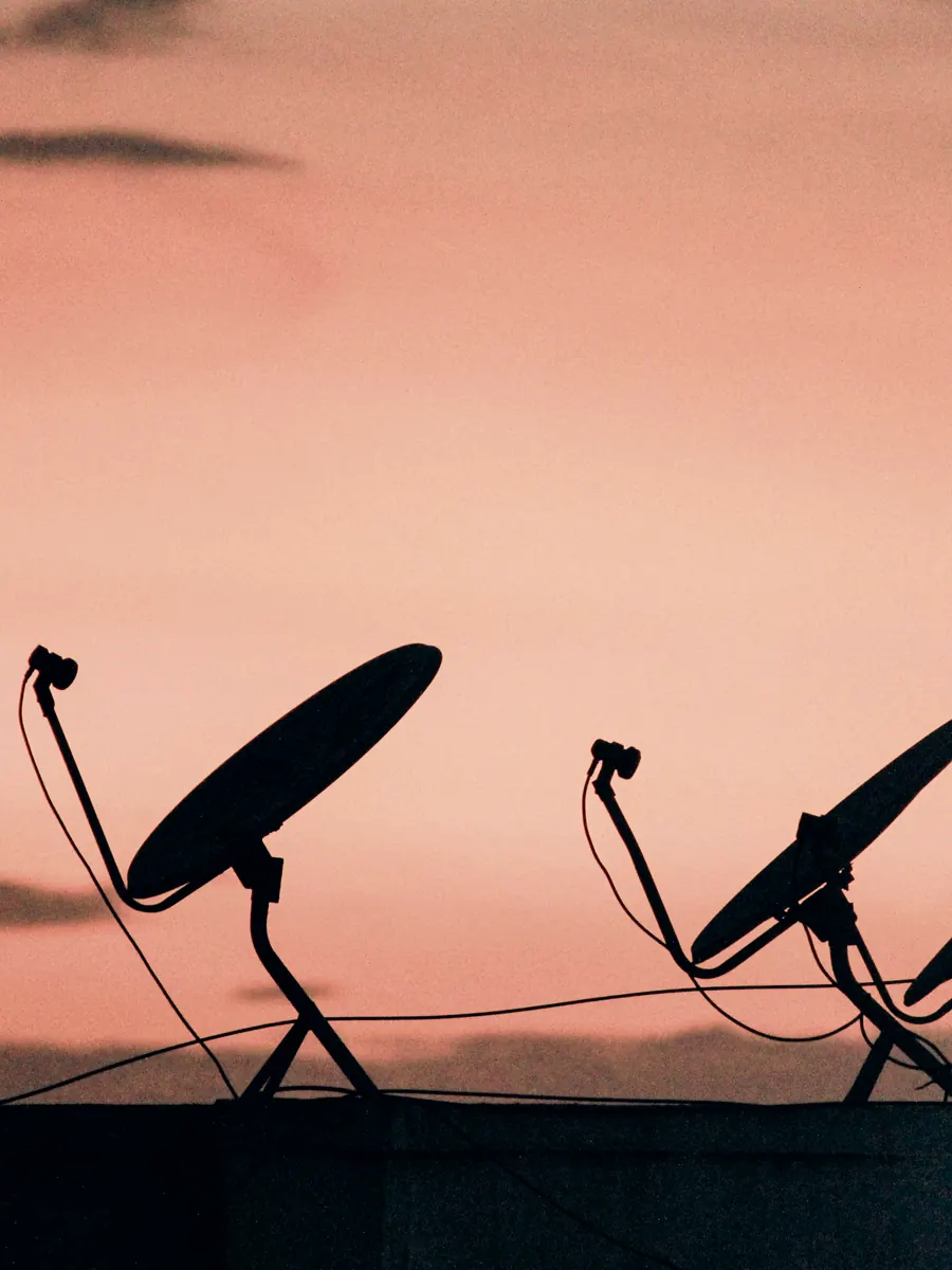 Satellite dishes silhouetted against a dusk sky.