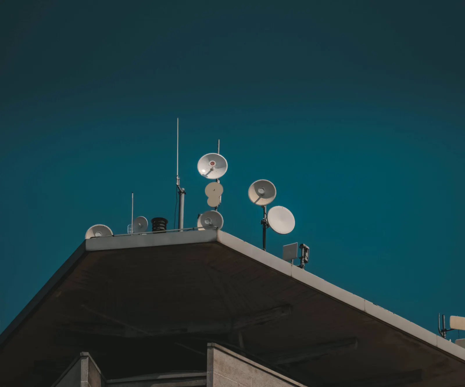 Communications antennas on a rooftop against a clear evening sky.